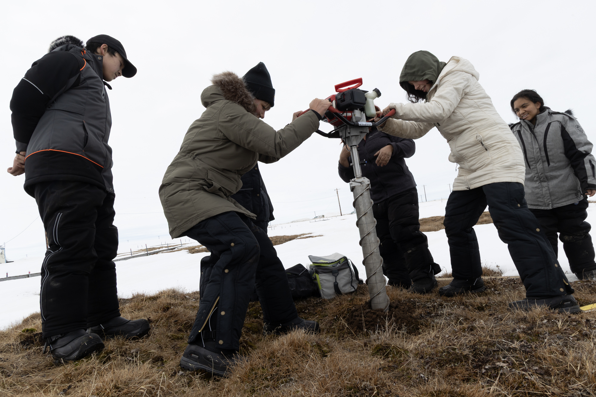 A group of summer camp students drill a permafrost core on the tundra