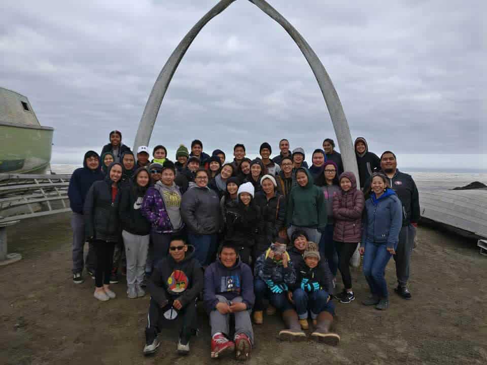 Students posing under the whale bone arch in Utqiaġvik