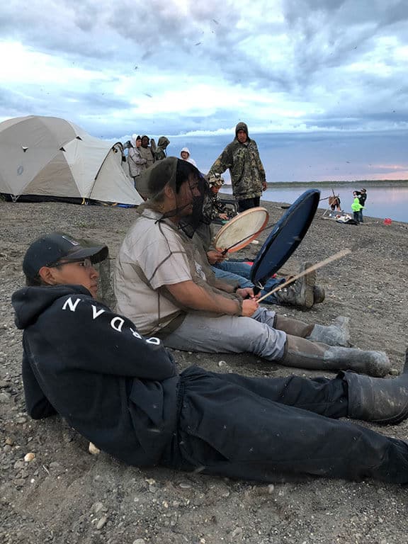 Group of students playing traditional drums on the beach of the Arctic Ocean.