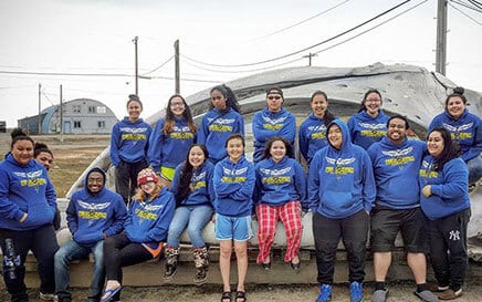 Group of Iḷisaġvik Allied Health students in program hoodies posing in front of whale skull.